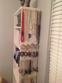 a white shelf filled with lots of bracelets and jewelry hanging on it's sides