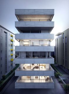 an apartment building with multiple levels and balconies on the second floor, at dusk