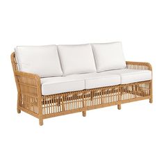 a wicker couch with white cushions on it