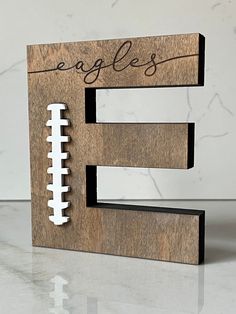 a wooden sign with a football on it and the word eagles written in black ink