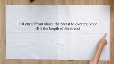 a person pointing at a piece of paper with the words, 10 cm = from above the breast to over the knee it's the length of the dress