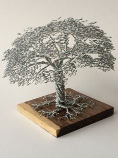 a wire tree sculpture sitting on top of a wooden board