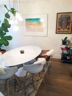 a dining room table with white chairs and a rug on the floor in front of it