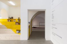 there is a yellow book shelf next to the stairs in this white room with bookshelves