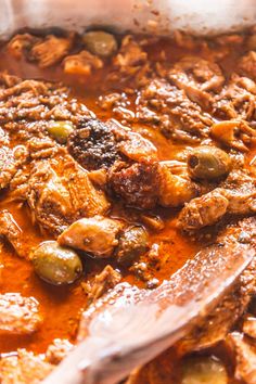 a stew with meat and olives in a large pot, ready to be eaten