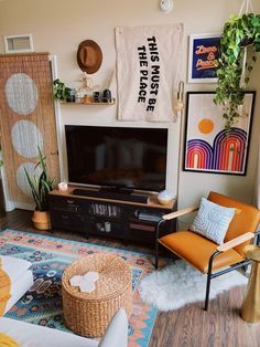 a living room with pictures on the wall and a television in the corner, as well as a wicker chair