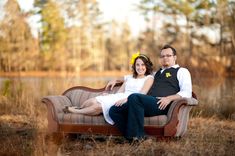 a man and woman sitting on top of a couch in front of a body of water