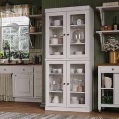 a kitchen with green walls and white cupboards filled with dishes on top of them