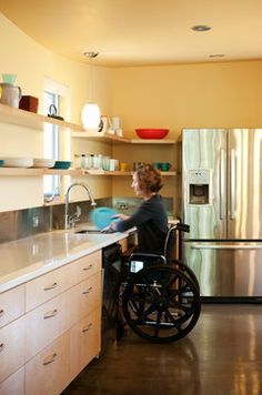 a woman in a wheel chair at the kitchen counter