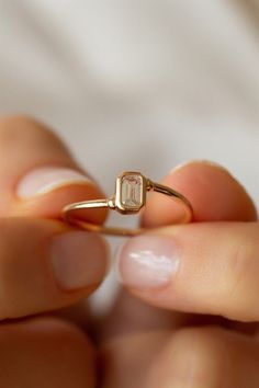 a woman is holding an engagement ring in her left hand, with the diamond on it's side