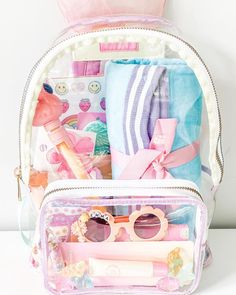 a pink and white backpack with various items in it