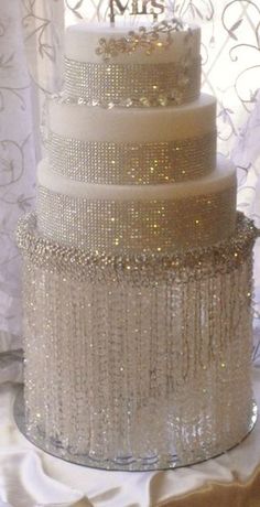 a three tiered cake sitting on top of a table next to a white curtain