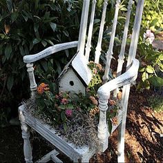 an old chair with flowers growing in it and a birdhouse on the back seat