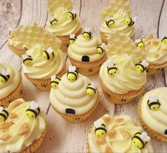 cupcakes with white frosting and honeybee decorations on top are sitting on a wooden table