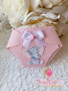 a pink box with an elephant on it next to some white flowers and a bouquet