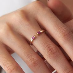 a woman's hand with two gold rings and one pink diamond ring on her finger