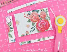 a pair of scissors sitting on top of a piece of fabric next to some flowers