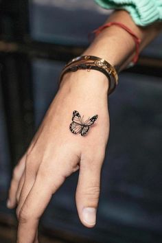 a woman's hand with a small butterfly tattoo on it