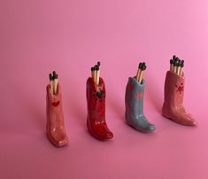 four different colored rubber boots with sticks sticking out of them on a pink and blue background