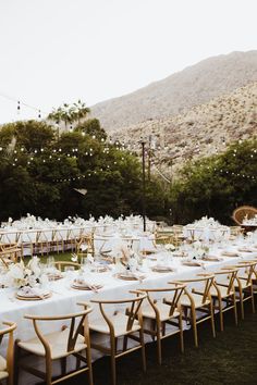 an outdoor dining area with tables and chairs set up for a wedding reception in the mountains