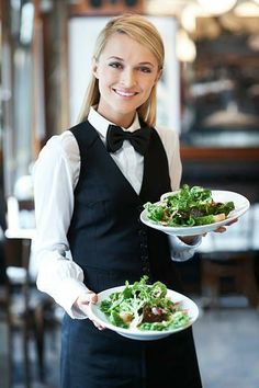 a waitress holding two plates of food in her hands