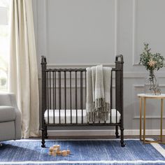 a baby's crib in the corner of a room with a blue rug