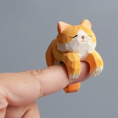 a tiny toy cat sitting on top of a finger