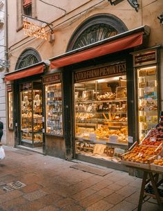 a woman walking down the street in front of a store with lots of pastries