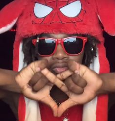 a person in a red hat and sunglasses making a heart with their hands