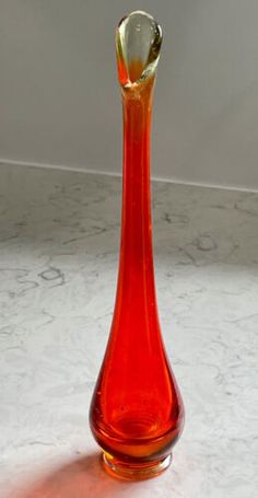 an orange vase sitting on top of a white table