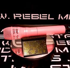 a pink microphone sitting on top of a table next to a black sign that says rebel music