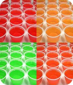 four different colors of liquid in plastic cups with the same color as each cup and one is red, green, yellow, or orange