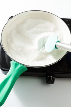 a green spatula is being used to stir something in a saucepan