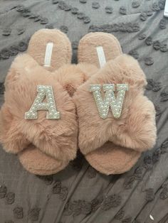 a pair of furry slippers with the letters a and w on them sitting on top of a bed