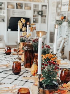 the table is set with candles, plates and vases for fall dinner party decorations