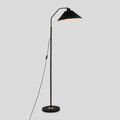 a black floor lamp with a white light on the base and a green shade over it