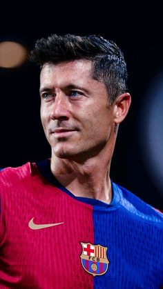 a close up of a soccer player wearing a red and blue uniform with his head turned to the side