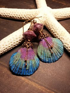 two seashells are sitting on top of a starfish with bead earrings