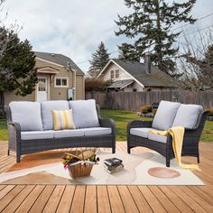 two wicker couches on a deck in front of a house with a yellow throw blanket