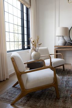 a living room with two chairs and a table in front of a large round mirror