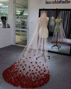 a wedding dress on display in front of a mannequin with red roses all over it