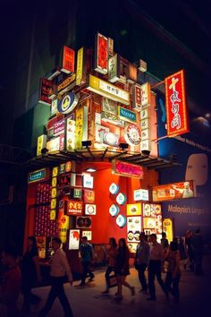 many people are walking around in front of a building that is lit up with neon signs