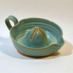 a small green bowl with a handle on it