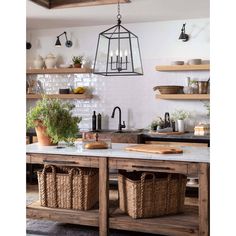 a kitchen island with baskets on it and lights hanging from the ceiling in front of it