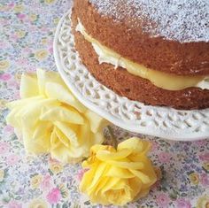 there is a cake on the table with yellow flowers next to it and two roses