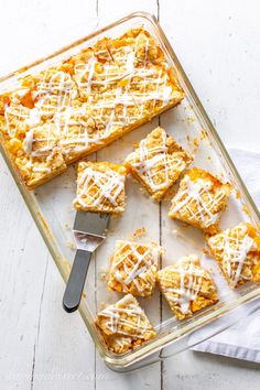 a pan filled with desserts on top of a white wooden table next to a spatula