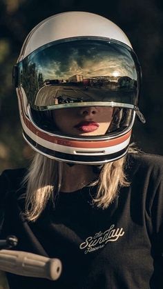 a woman wearing a motorcycle helmet with her reflection in the side mirror on her face