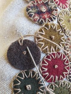 an assortment of buttons and needles on a piece of cloth