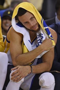 a man with a towel wrapped around his head sitting on a bench at a basketball game