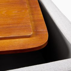 a close up view of a wooden tray on a table with white linens in the background